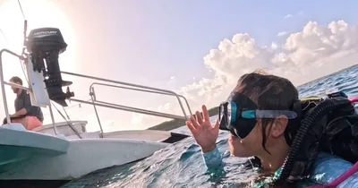A scuba diver beside the dive boat at sunset